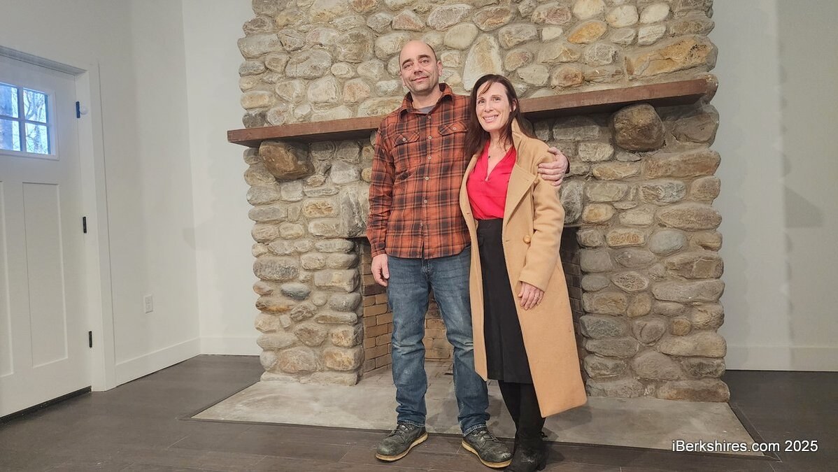 Rob and Kristin Hinton standing at the restored stone fireplace in the finished building