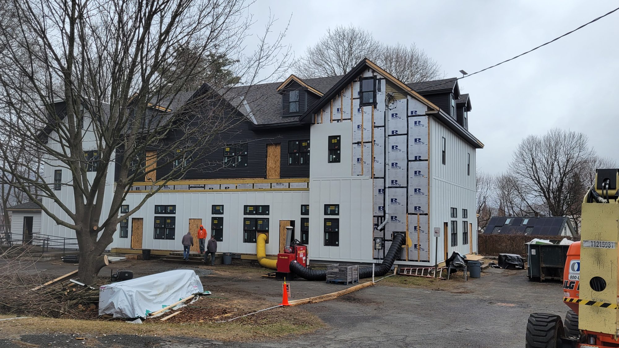 Crew installing black and white siding on the rebuilt building