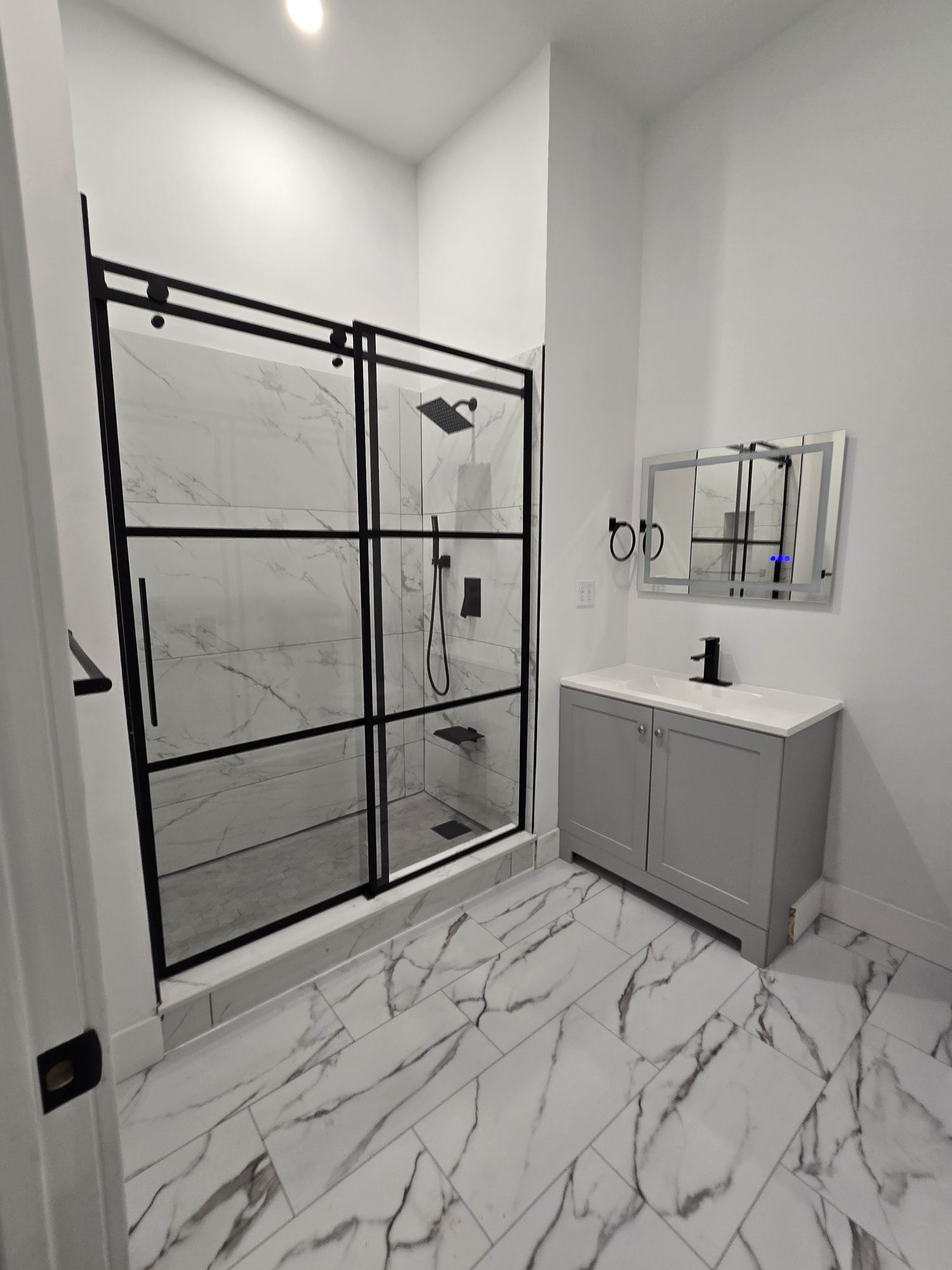 Finished bathroom with marble tile and a glass shower